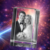 A 3D rectangular crystal block featuring a black and white laser-etched wedding portrait of a smiling couple, set against a vibrant, glowing purple and orange cosmic galaxy background with light bursts.