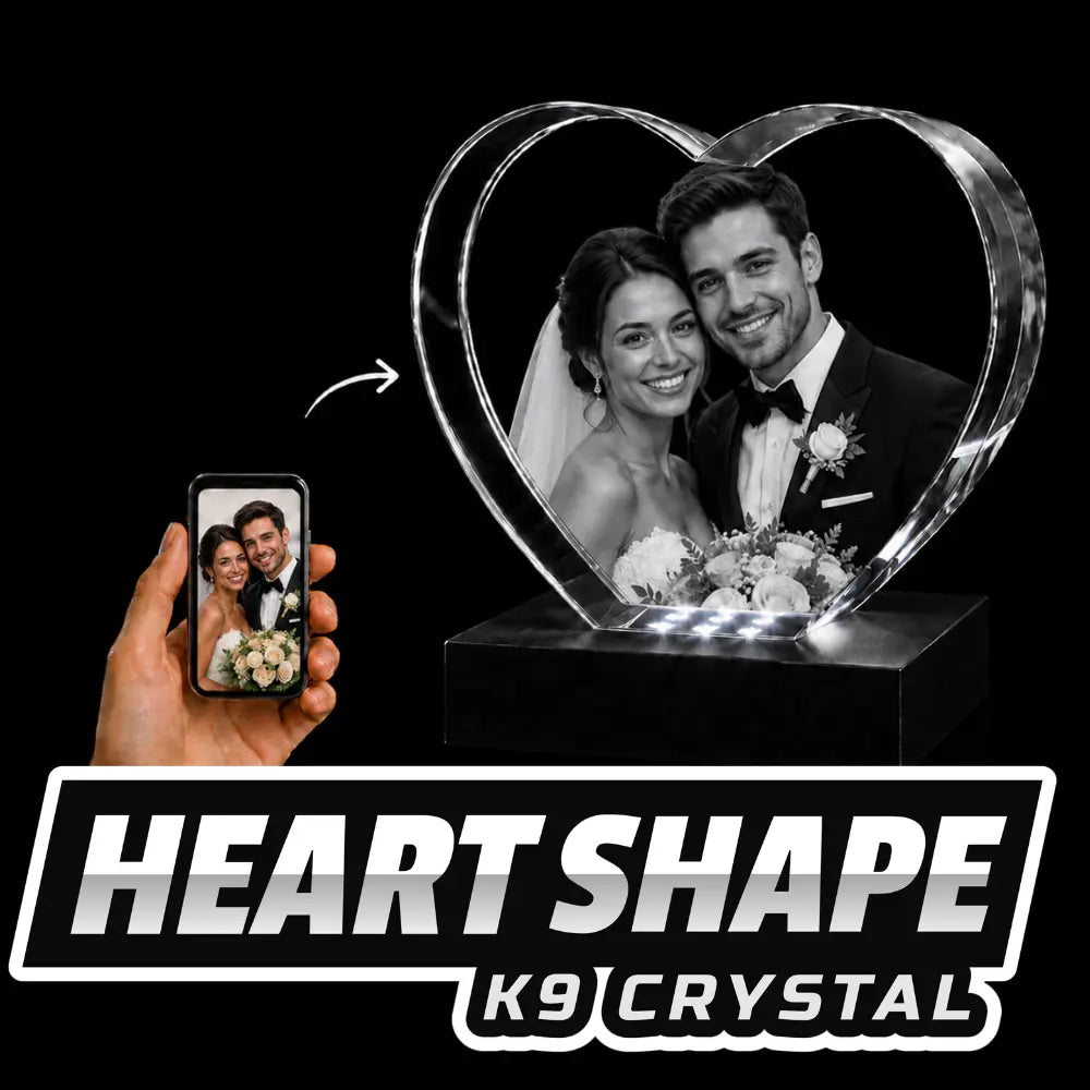 A heart-shaped K9 crystal engraved with a 3D wedding portrait of a bride and groom, sitting on a glowing light-up pedestal.